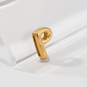 Detailed close-up of a gold-plated stainless steel letter pendant charm on a clean minimalist stage.