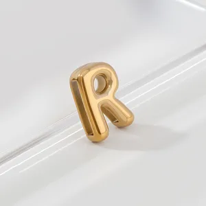 Close-up detail shot of a gold-toned 3D letter R pendant charm, showing polished metallic texture.
