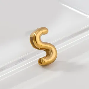 Close up detail shot of shiny gold stainless steel letter S pendant minimalist jewelry item