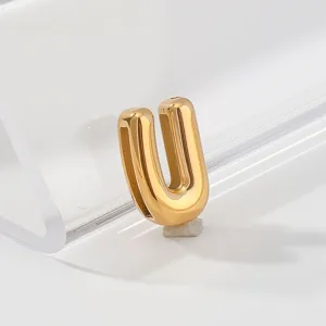 Close-up detail of a minimalist gold stainless steel letter U charm pendant, polished finish.
