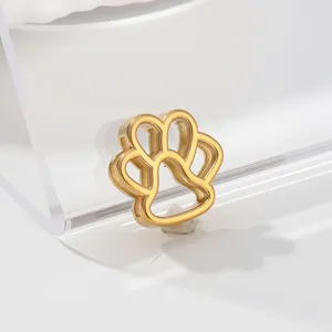 Close-up of a delicate gold-tone animal paw print metal charm pendant, premium design detail view.