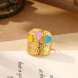 Close-up weergave van roestvrijstalen gehamerde open ring met kleurrijke emaille druppeldetails.