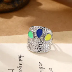 Close-up van de massieve roestvrijstalen open ring met kleurrijke emaillen druppels en textuur.