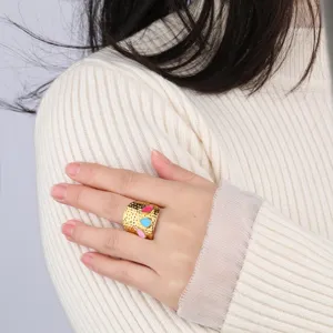 Brede roestvrijstalen open ring met kleurrijke druppel emaille details op hand model, hoofdweergave.