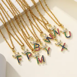Primo piano dettagliato di collane con ciondolo lettera corona dorata e zirconi colorati.