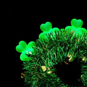 Close-up detail of St. Patrick's Day green tinsel headband with glowing shamrock lights.