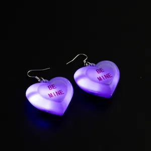 Primo piano di orecchini a cuore LED viola luminosi, dettaglio pendente amore trasparente.
