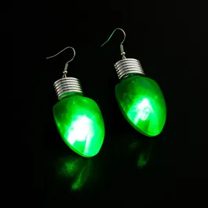 Detailaufnahme leuchtender grüner Weihnachts-Glühbirnen-Ohrringe mit silbernen Haken für Partys.