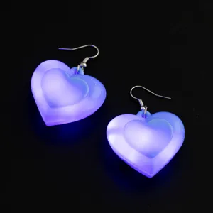 Dettaglio in primo piano di orecchini pendenti a cuore viola luminosi con luci LED per feste.