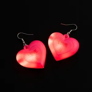 Dettaglio ravvicinato di orecchini a cuore rosa luminosi con luce LED per feste.