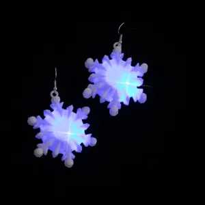 Gros plan de boucles d'oreilles flocon de neige LED lumineuses avec un éclairage bleu.