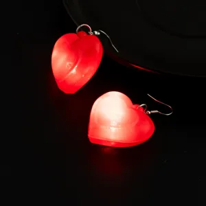 Primo piano di orecchini a cuore rosso luminoso con luce LED, dettaglio di gioielli per feste.