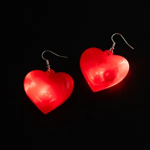 Primo piano di orecchini a cuore rossi luminosi con ganci in metallo, dettaglio per feste.
