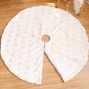 Jupe de sapin de Noël en peluche blanche avec flocons de neige dorés pour décoration de fête.