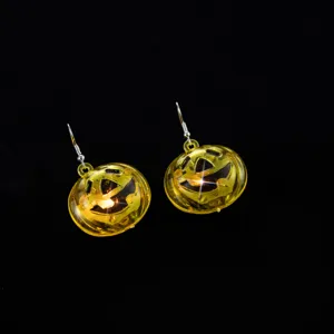 Nahaufnahme der leuchtenden gelben Kürbis Ohrringe für Halloween Party Accessoires.