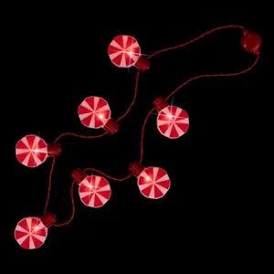 Primer plano de luces de cadena de caramelos de menta rojos y blancos con LED en un fondo negro.