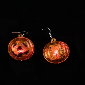 Nahaufnahme von leuchtenden LED Kürbis Ohrringen für Halloween Party Kostüm Schmuck.