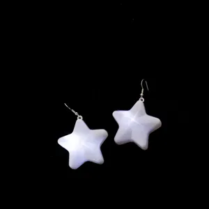 Close-up detail shot of glowing star earrings, shining pentagram pendant with metal hook.