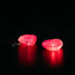 Close-up detail of glowing red LED heart earrings, featuring bright light effect in dark.