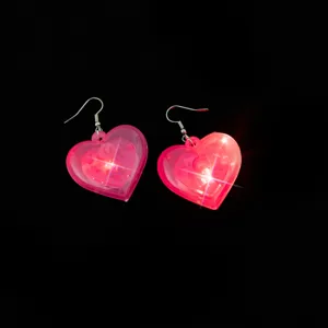 Detailed close-up of glowing pink heart-shaped earrings featuring bright LED lights in the dark.