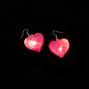 Close-up of glowing pink heart LED earrings, vibrant lighting effect, chic accessory.