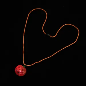 Detailed shot of LED glowing Halloween pumpkin pendant necklace, festive party accessory item.