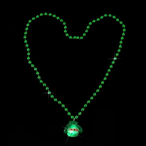 Primo piano della collana di perle verdi con ciondolo maglione luminoso, dettaglio festivo.