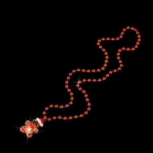 Primo piano sul dettaglio del ciondolo luminoso a forma di omino di pan di zenzero e collana.