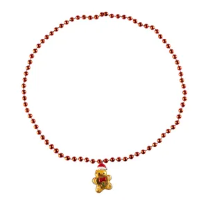 Primo piano dettagliato della collana di perle rosse natalizie con ciondolo omino.