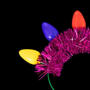 Close up detail of glowing Christmas tinsel headband featuring colorful light bulbs.