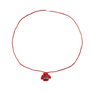 Dettaglio in primo piano della collana con ciondolo maglione natalizio con cordino rosso e motivo.