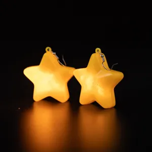 Detailed close-up of glowing yellow star earrings featuring a luminous design and dark background.