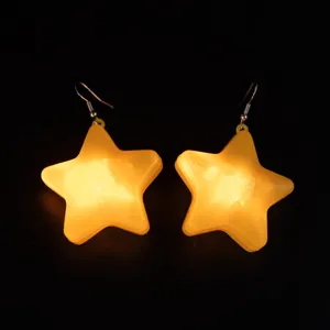 Close-up detail of glowing star earrings, luminous yellow pentagram design with metal hooks.