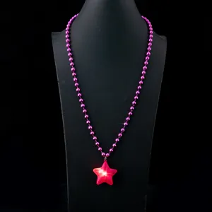 Nahaufnahme des leuchtenden Sternanhangs und der rosa Perlenkette für festliche Partys.