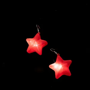 Detail rode ster oorbellen, feestelijk sieraden met roostertextuur en helder gloeiend effect.
