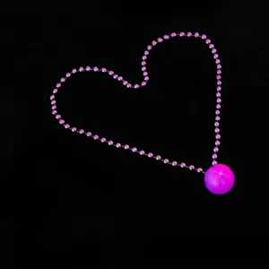 Close-up of a glowing pink bead necklace arranged in a heart shape for party and nightclub use.