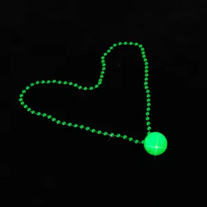 Detail view of glowing green bead necklace and disco ball pendant for party events.