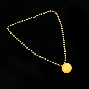 Detailed view of a glowing yellow ball pendant necklace with gold bead chain for party club night.