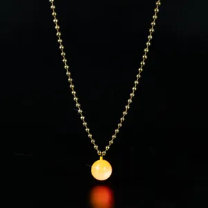 Carnival glowing necklace detail showing the luminous yellow disco ball pendant and gold bead chain.