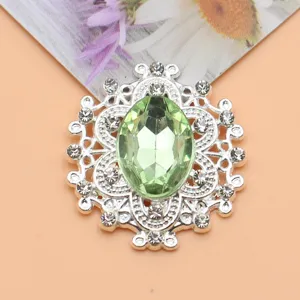Detailopname van de sprankelende ovale groene strass knop met filigraan metaal ontwerp.