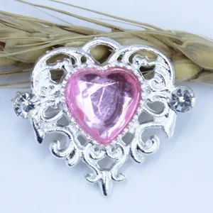 Close-up detail of heart rhinestone alloy DIY accessory with pink crystal and filigree.