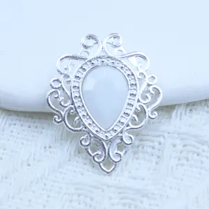 Close-up van zilveren filigraan hanger met witte druppelsteen voor handgemaakte sieraden.