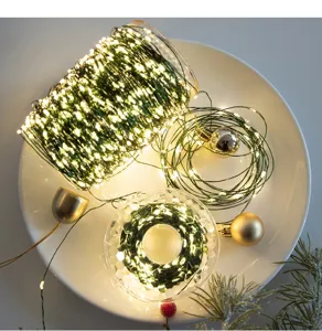 Primo piano di luci di Natale con filo verde e LED caldi su piatto bianco decorato.