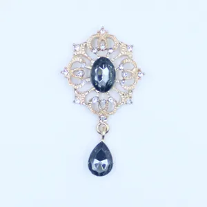 Detail van gouden legering hanger met strass-steentjes en donkere druppelvormige kristalstenen.