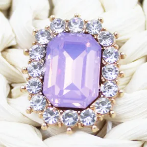Close-up detail of rectangular purple crystal rhinestone button with gold alloy base and clear stones.