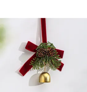 Close-up of Christmas red velvet bow pendant with golden bell, pinecones and pine needles.