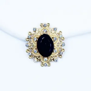 Close-up detail of the gold alloy oval rhinestone button featuring a central black gemstone.