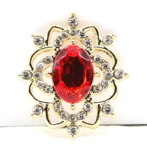 Close-up of gold alloy flower filigree base with red resin rhinestone for DIY jewelry crafts.