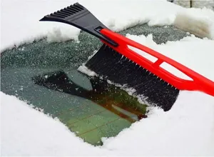 Car snow brush and ice scraper detail view showing winter windshield cleaning in action.