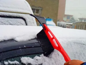 Detail view of the car snow shovel brush in action, clearing snow and ice from vehicle roof easily.